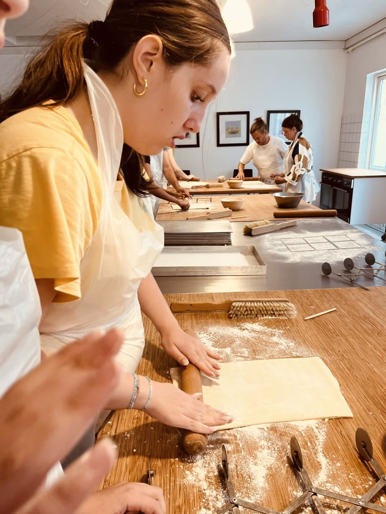  Hands-on Danish pastry baking workshop in Copenhagen, with pastries on trays and participants preparing dough.
