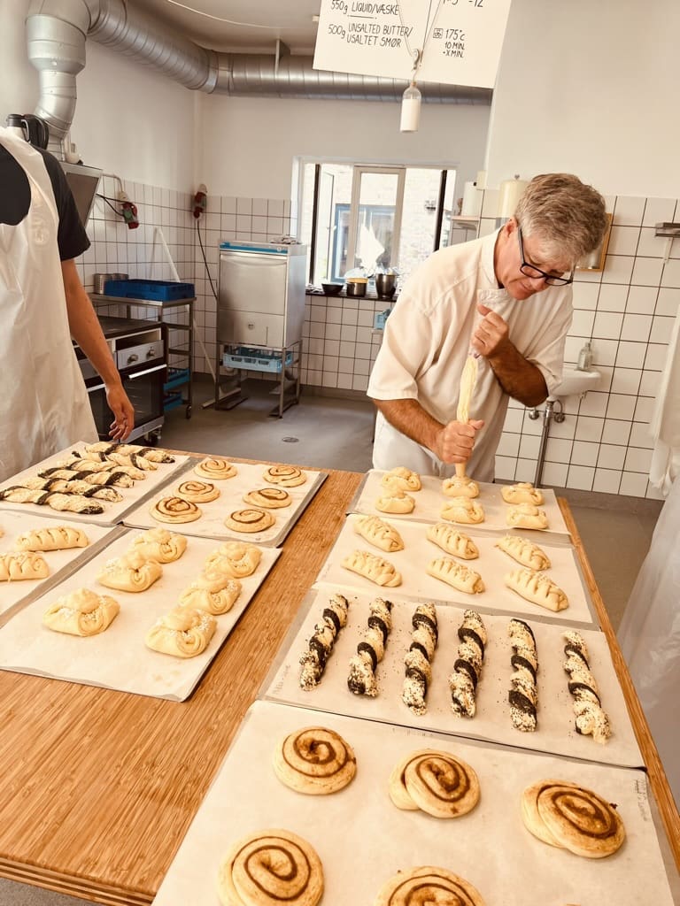  Hands-on Danish pastry baking workshop in Copenhagen, with pastries on trays and participants preparing dough.
