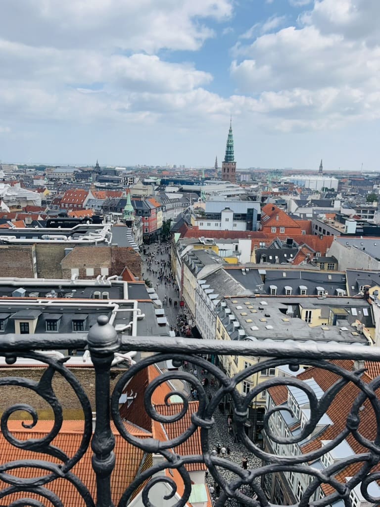 Panoramic view of Copenhagen from the top of the Round Tower, showing rooftops, city streets, and a clear skyline.