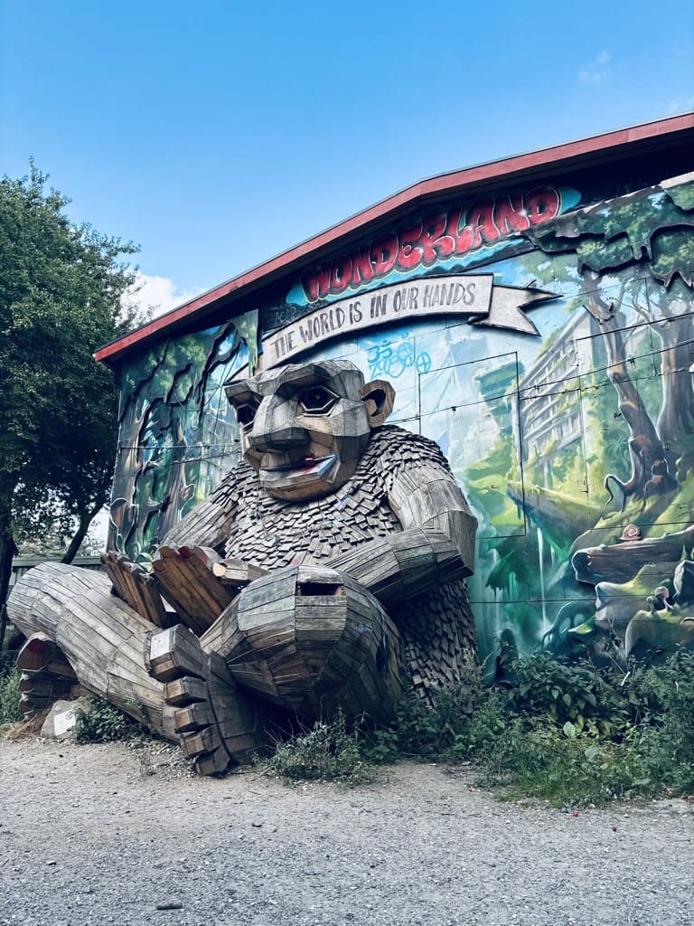 Street in Freetown Christiania, Copenhagen, showing colorful murals, creative houses, and leafy paths in an alternative neighborhood.