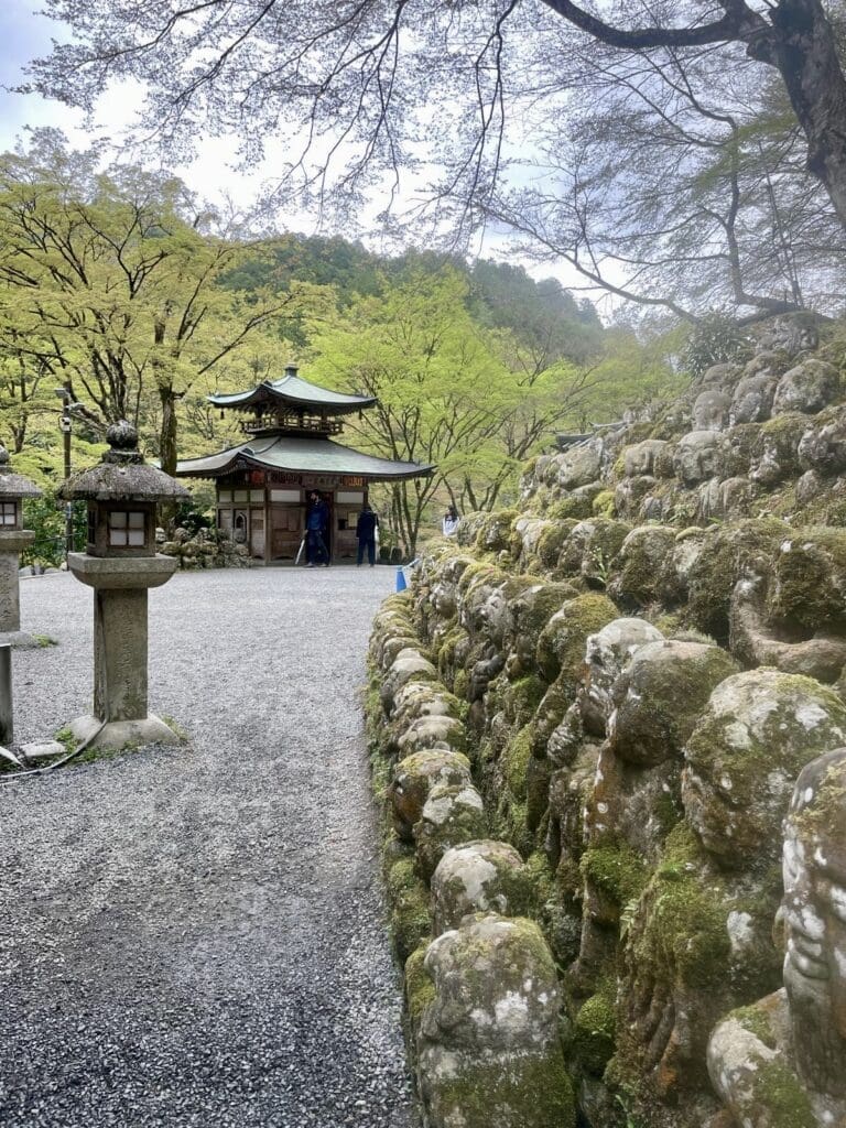 Stone statues lining a moss-covered path at Otagi Nenbutsu-ji Temple in Kyoto, Japan